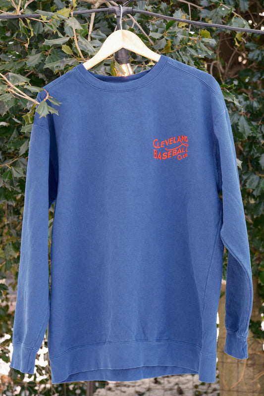 Vintage blue Cleveland Baseball Club sweatshirt hanging outdoors, showcasing red embroidered logo and soft premium fabric.