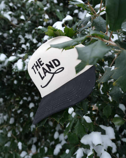 5 panel hat with 'The Land' text on a snowy background
