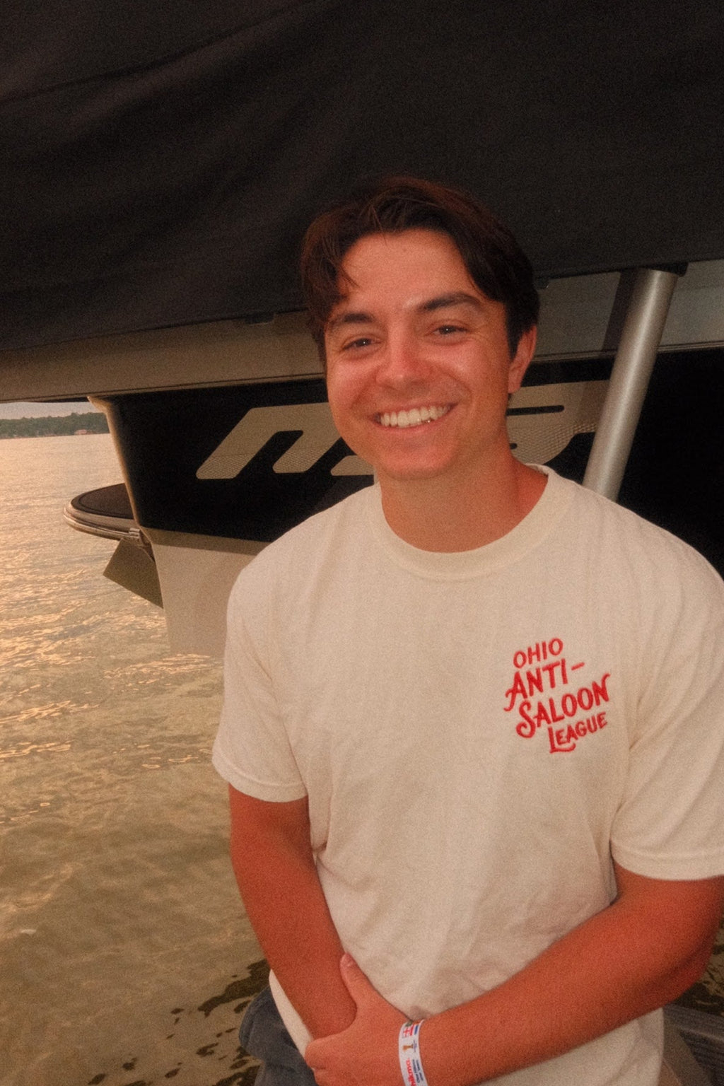 Ivory Ohio Anti-Saloon League Tablespoon heavyweight t-shirt worn on a dock, front graphic reading Ohio Anti-Saloon League