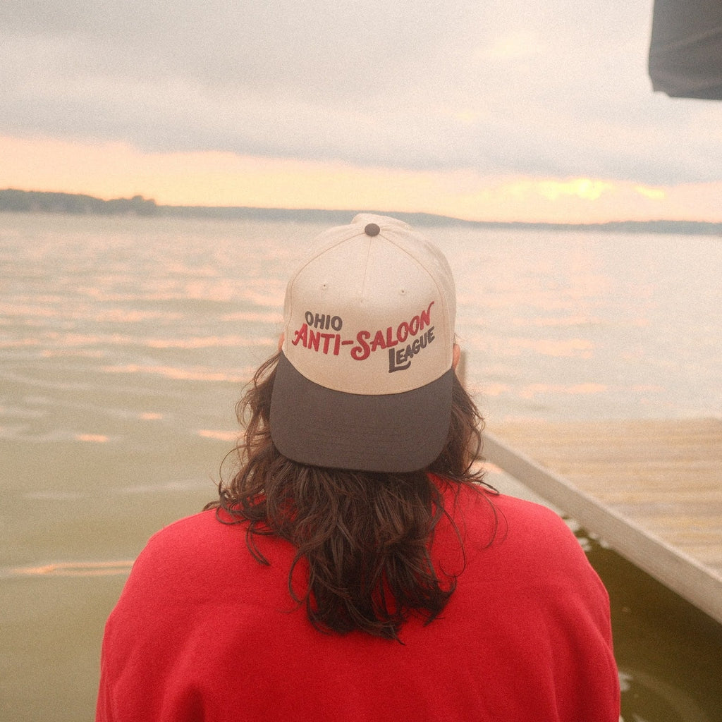White and dark grey Ohio Anti-Saloon League two-tone cap worn on a dock overlooking a lake
