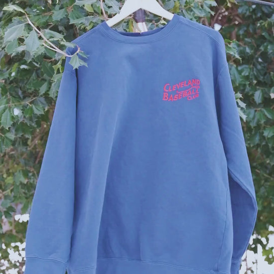 Blue Cleveland Baseball Club sweatshirt on hanger outdoors, red embroidered logo highlights vintage crewneck appeal.