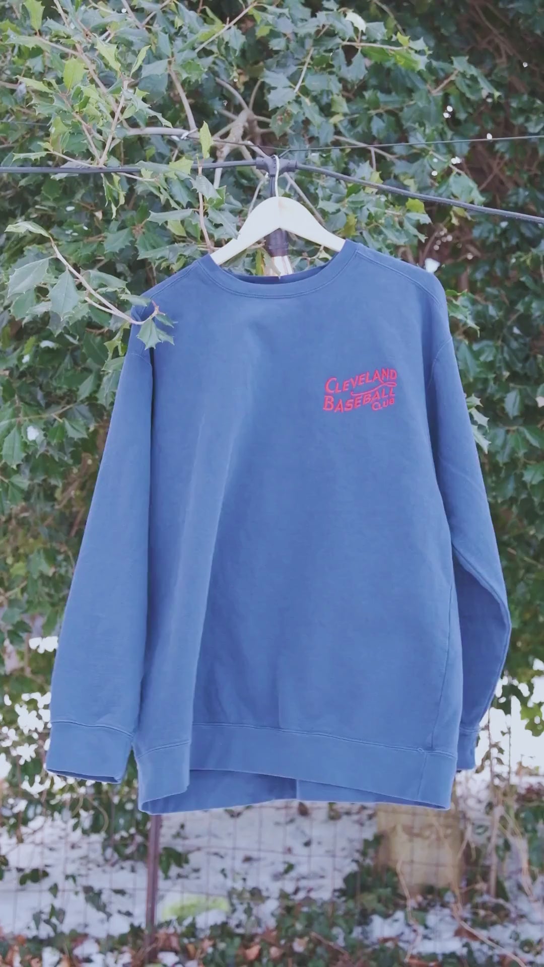 Blue Cleveland Baseball Club sweatshirt on hanger outdoors, red embroidered logo highlights vintage crewneck appeal.